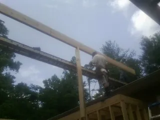 Carpenter setting a ridge beam over a new addition frame — Ice Dam Removal by Roofing Brothers in New River